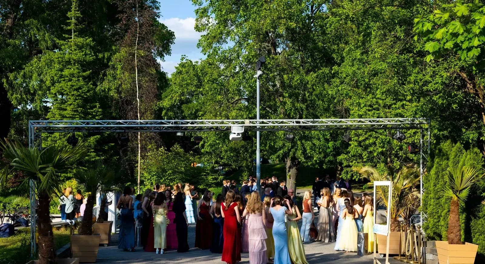 Treor i balklänningar och kostymer samlas utomhus inför studentbalen.
