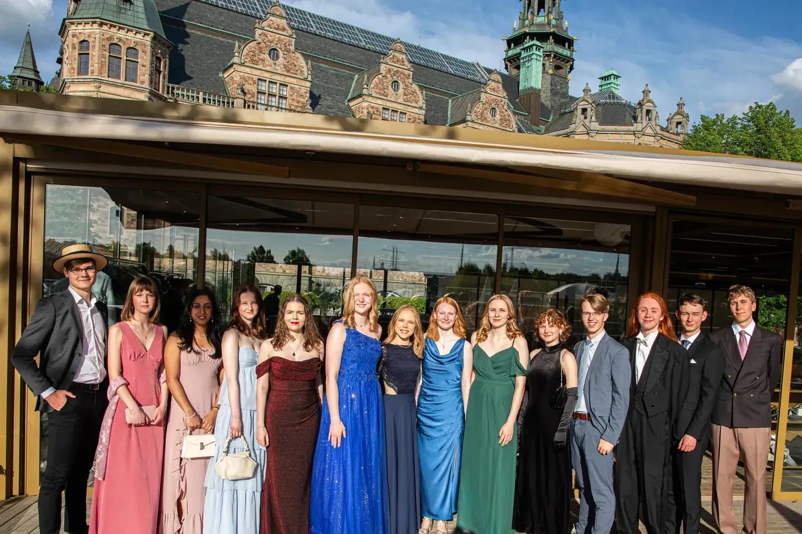 Gruppbild på treor i balklänningar och kostymer på en terrass före balmiddagen.