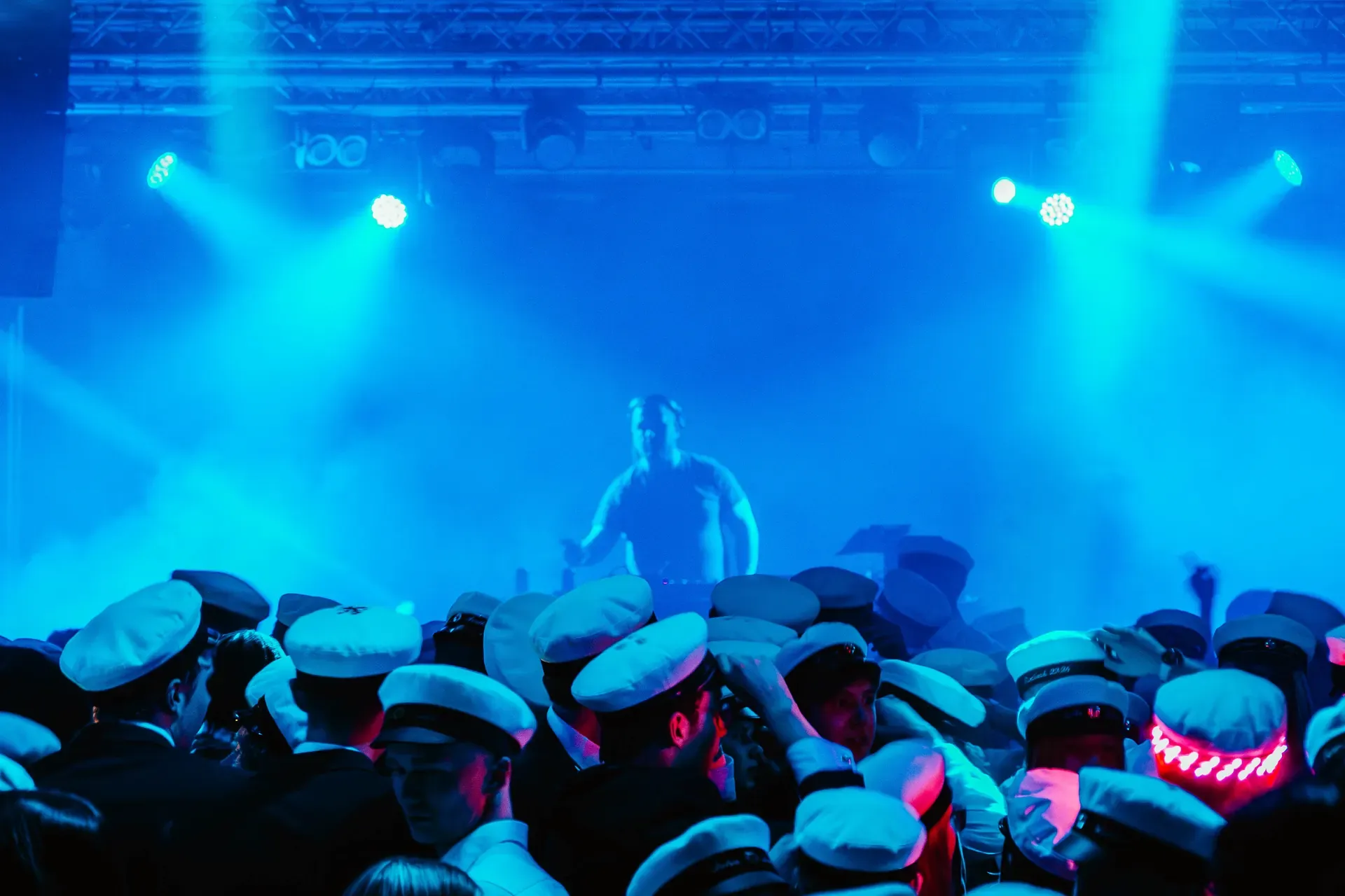 Blått scenljus och spotlights över en publik i studentmössor framför scenen.